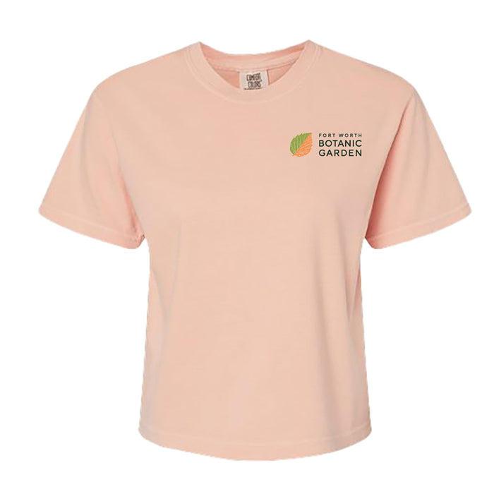 Light peach, short-sleeved, boxy Fort Worth Botanical Garden Women’s Boxy T-Shirt featuring a leaf logo and the text Fort Worth Botanic Garden on the left chest.