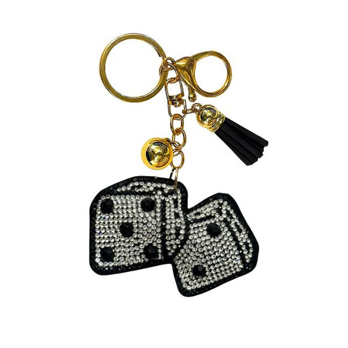 The Bling Dice Bag Charm features a gold keychain adorned with a black tassel, a small gold bell, and two black-and-silver rhinestone dice charms—making it the perfect stylish accessory for your next tabletop gaming night.