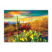 The Desert Colors Saguaro Flowers 1000pc Puzzle depicts a desert landscape at sunset with a tall saguaro cactus and prickly pear cacti under a multi-hued sky.