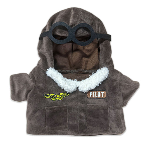 The Plushy's Closet Aviator Costume features a small brown jacket with white fleece trim, a hood with black goggles, and two patches—yellow wings and a PILOT label—ideal for imaginative play with your favorite stuffed animal or doll.