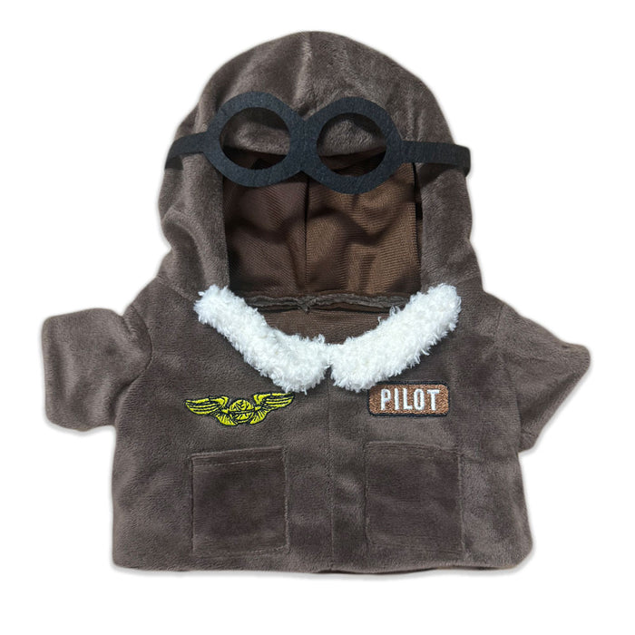 The Plushy's Closet Aviator Costume features a small brown jacket with white fleece trim, a hood with black goggles, and two patches—yellow wings and a PILOT label—ideal for imaginative play with your favorite stuffed animal or doll.