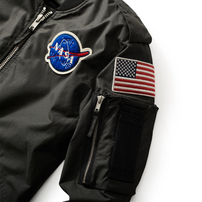 The Men’s NASA Flight Jacket is a black men’s jacket with a NASA patch on the chest, a U.S. flag patch and zippered pocket on the sleeve, plus a Velcro patch, channeling classic astronaut jacket style.