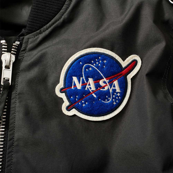 Close-up of the Men’s NASA Flight Jacket in black, showcasing a prominent blue NASA logo patch adorned with white stars, a bold red swoosh, and “NASA” in striking white lettering. A silver zipper is partially visible on the left side of the image, highlighting the classic details of this iconic space exploration jacket.