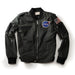 The Men’s NASA Flight Jacket is a black jacket inspired by authentic NASA Flight Jacket designs, featuring a NASA patch on the chest and an American flag patch on the left sleeve, displayed on a white background.