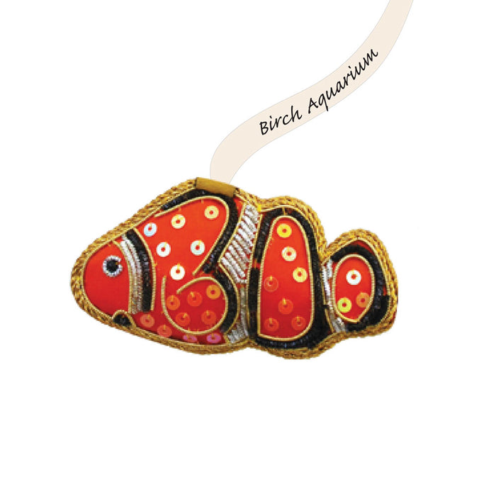 A beaded clownfish ornament with a ribbon tag labeled Birch Aquarium.