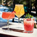 Three Christmas Cocktails in various glassware, including one with a red sugared rim, one with orange slices, and one topped with pomegranate seeds and mint.