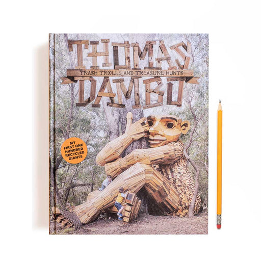 A hardcover copy of Trash, Trolls and Treasure Hunts featuring a photograph of a giant troll sculpture sitting in a forest next to a yellow pencil.