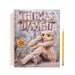 A hardcover copy of Trash, Trolls and Treasure Hunts featuring a photograph of a giant troll sculpture sitting in a forest next to a yellow pencil.