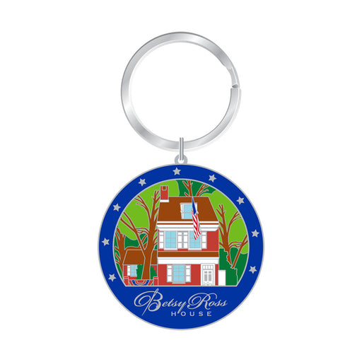 The Betsy Ross House Layered Keychain is a round accessory showcasing an illustration of the iconic landmark, bordered by white stars against a blue background and finished with the “Betsy Ross House” text at the bottom. This patriotic keychain makes a perfect way to celebrate America’s heritage and history.