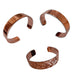 Three USSCM Reclaimed Copper Bracelets—one smooth, one hammered, and one intricately engraved—are hand-crafted in the USA from USS Constitution copper and feature open ends arranged in a triangle.