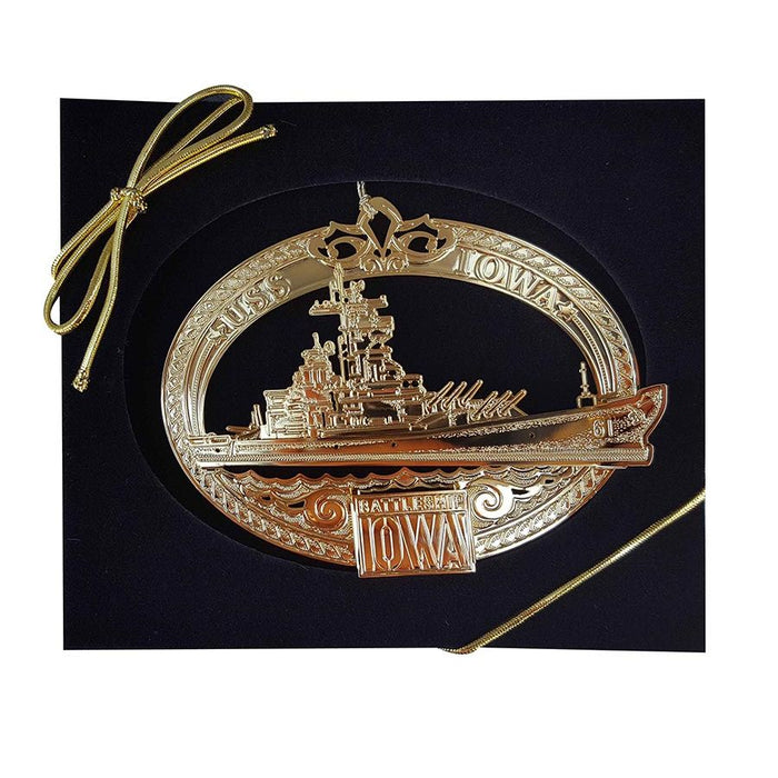The USS Battleship IOWA Ornament is gold plated, engraved with “USS IOWA” and “Battleship IOWA,” displayed on a black background, and includes a gold ribbon for hanging.