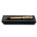 An Americana Pens and Pencils wood pen with metal accents, engraved "USS Constitution," rests on a closed black box against a white background.